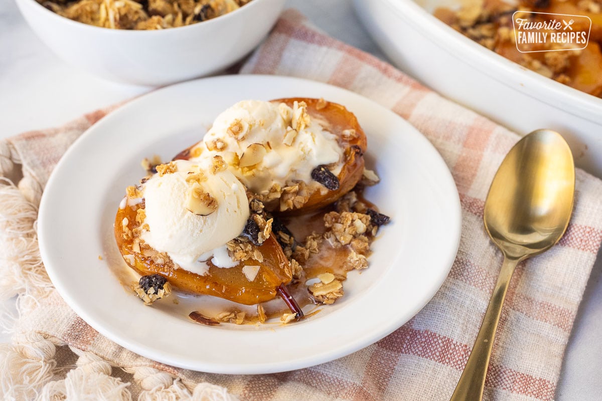 Two baked pear slices on a plate with granola and vanilla ice cream.