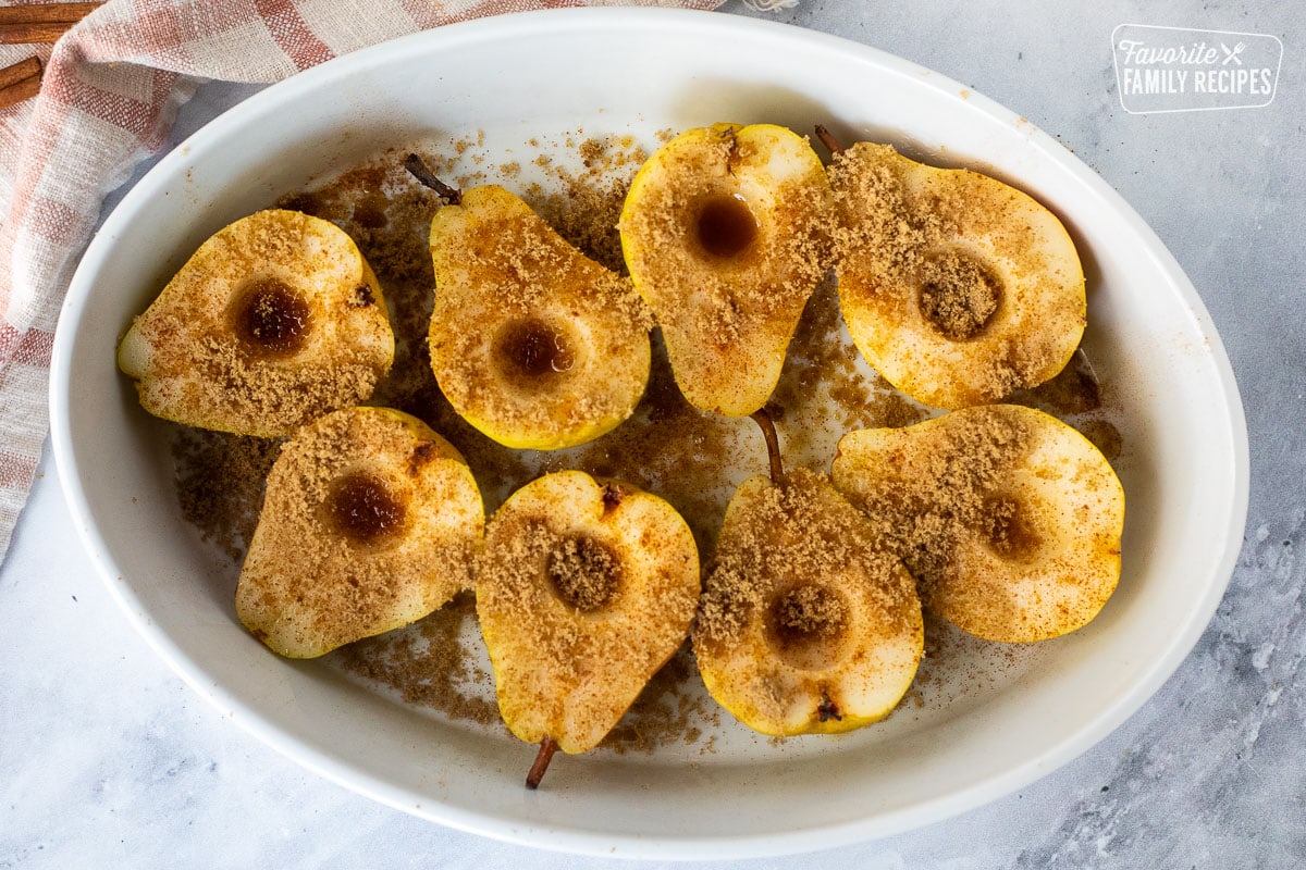 Pears with cinnamon, apple pie spice, and dark brown sugar sprinkled on top in a baking dish.