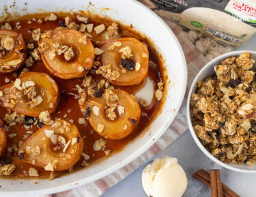 Baked pears next to a bowl of granola and scoop of vanilla ice cream.