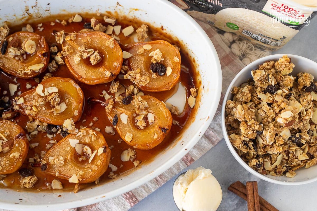 Baked pears next to a bowl of granola and scoop of vanilla ice cream.