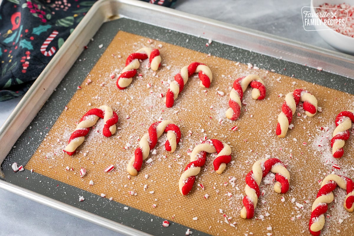 Twisted candy Cane cookies on a baking sheet with crushed candy canes sprinkled over the top.