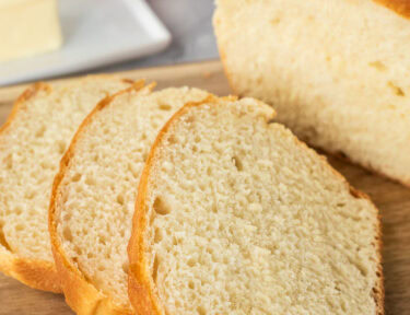 Sliced loaf of baked bread on a cutting board.