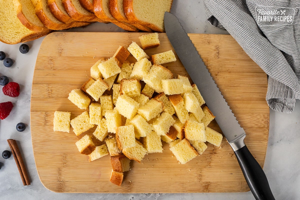 Cutting board with a bread, knife and cubed brioche bread.