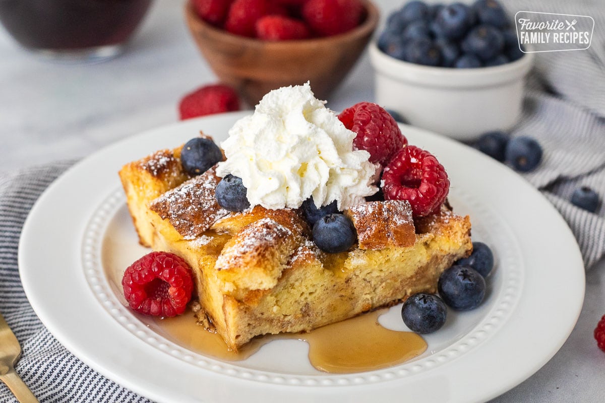 Plate with brioche French toast casserole, fresh blueberries, and raspberries and syrup.