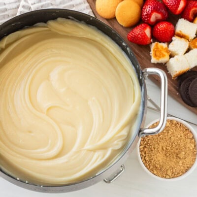 Cheesecake Fondue next to cutting board of cookies, cake and strawberries.