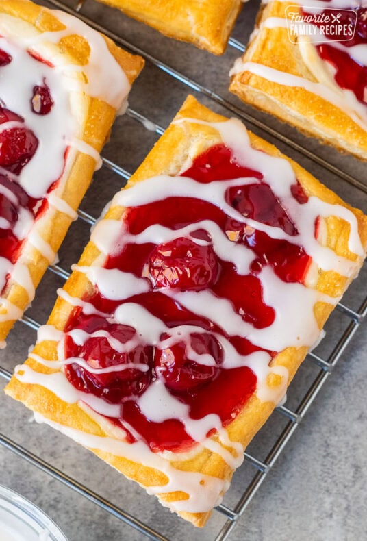 Cherry danish drizzled with white icing on a cooling wired rack.