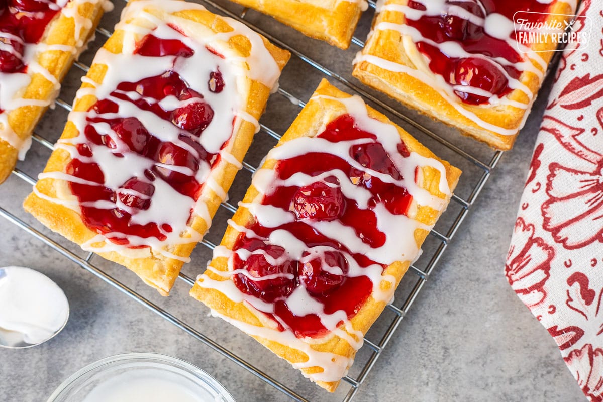 Cherry danishes on a cooling rack with white icing.