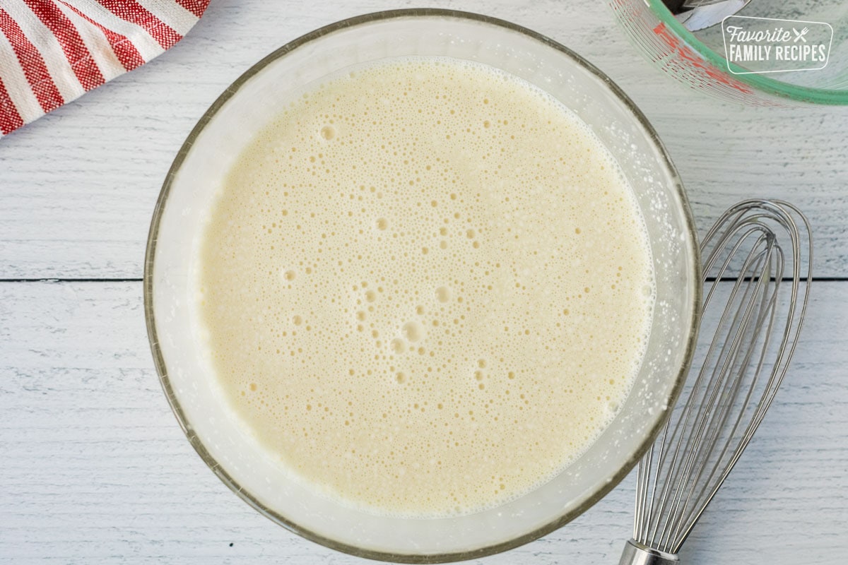 Marshmallow mixture in a glass mixing bowl with a whisk on the side.