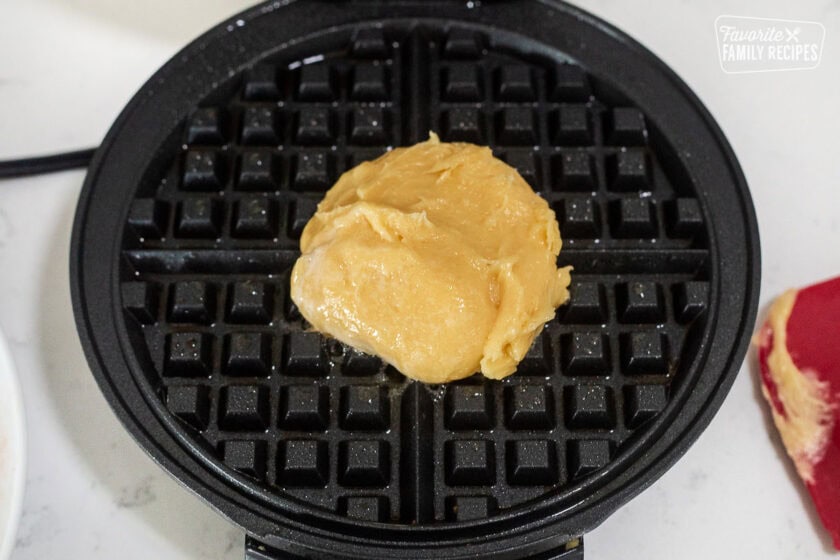 Sprayed waffle iron with a blob of churro waffle batter in the middle.