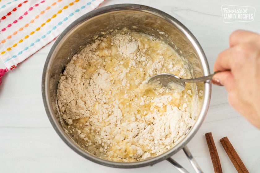 Stirring a saucepan with flour and butter mixture with a spoon.