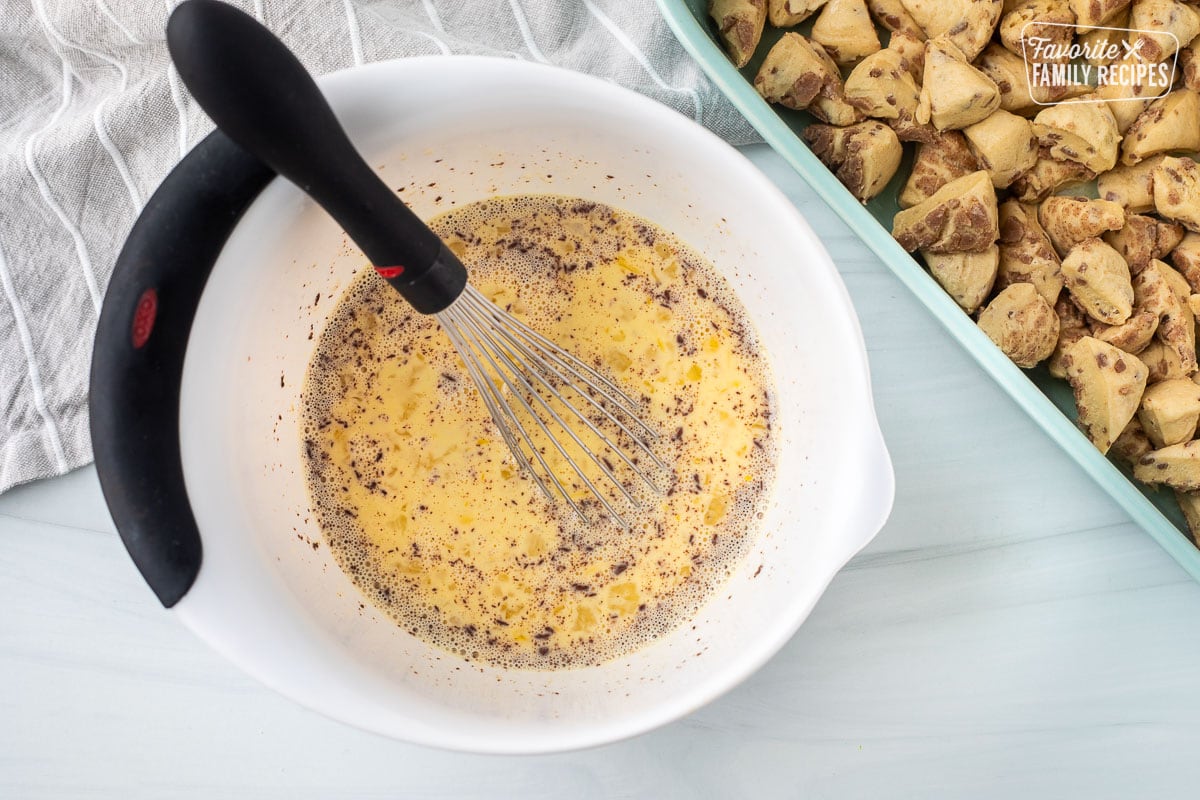 Mixing bowl with egg mixture and baking dish with cut up cinnamon dough.