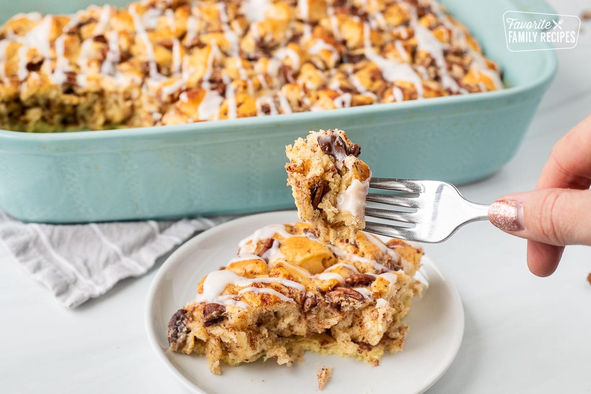 Fork with a piece of Cinnamon Roll Casserole held over plate.