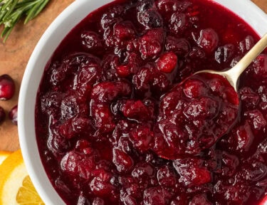 Bowl of orange cranberry sauce and a spoon.