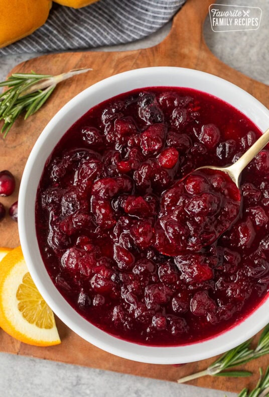 Bowl of orange cranberry sauce and a spoon.