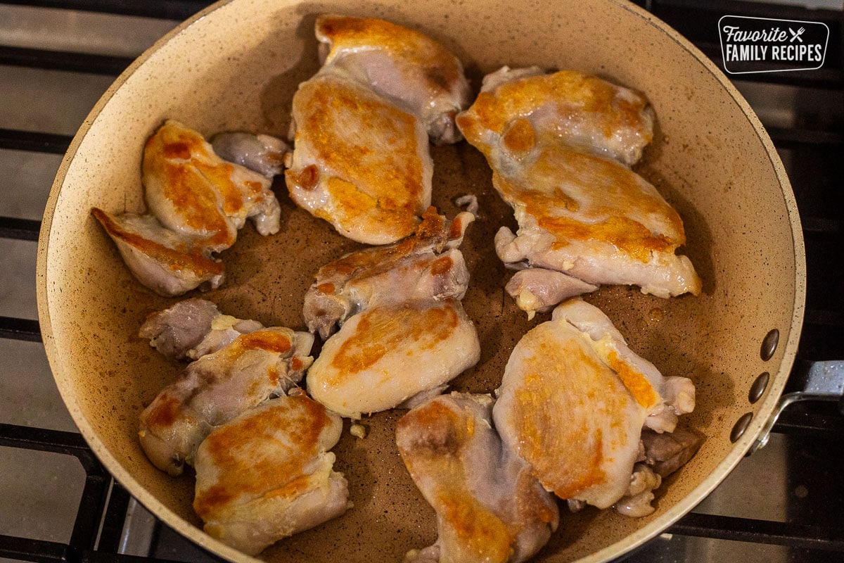 Chicken thighs seared in a skillet.