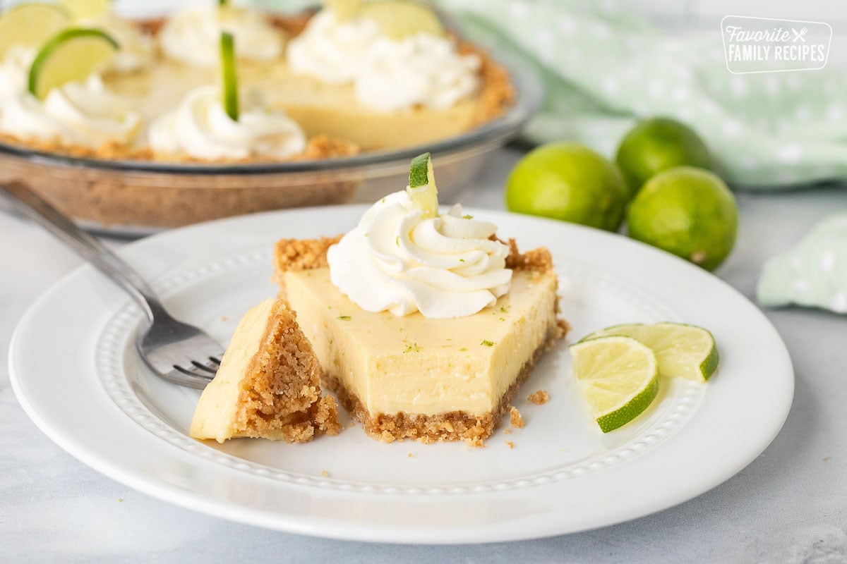 Fork cutting a bite-sized piece of Key Lime Pie slice, showing creamy texture.