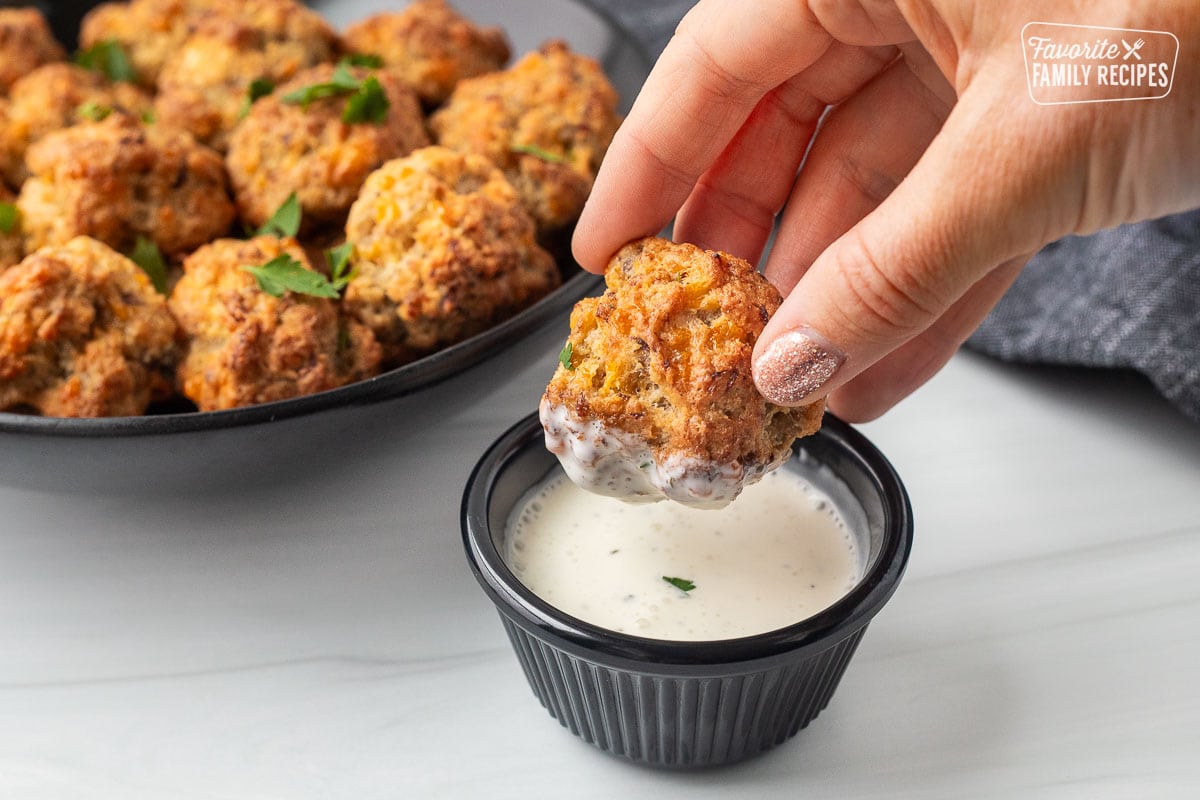 Hand holding a Red Lobster Sausage Ball dipped in Ranch dressing.