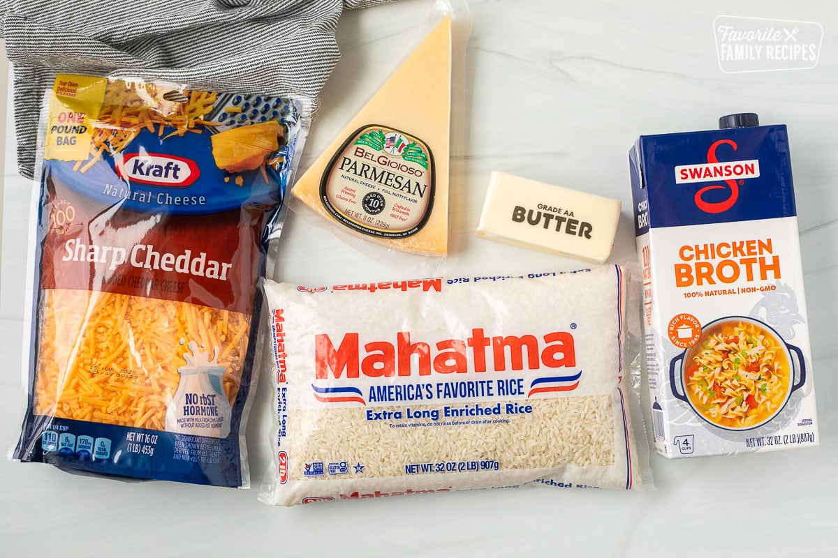 Ingredients to make Easy Cheesy Rice including shredded sharp cheddar cheese, parmesan cheese, butter, rice and chicken broth.