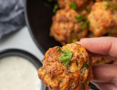 Hand holding a Red Lobster Sausage Ball with cup of Ranch dressing.