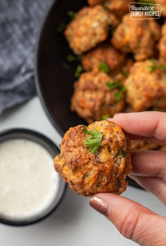 Hand holding a Red Lobster Sausage Ball with cup of Ranch dressing.