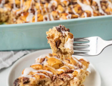 Cinnamon Roll Casserole on a fork held over plate.