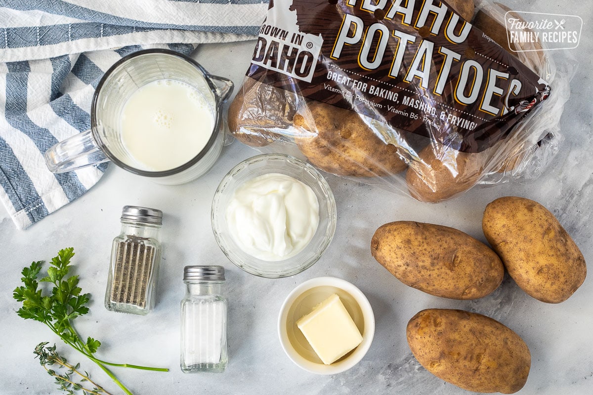 Ingredients to make homemade mashed potatoes, including potatoes, sour cream, milk, butter, salt and pepper.