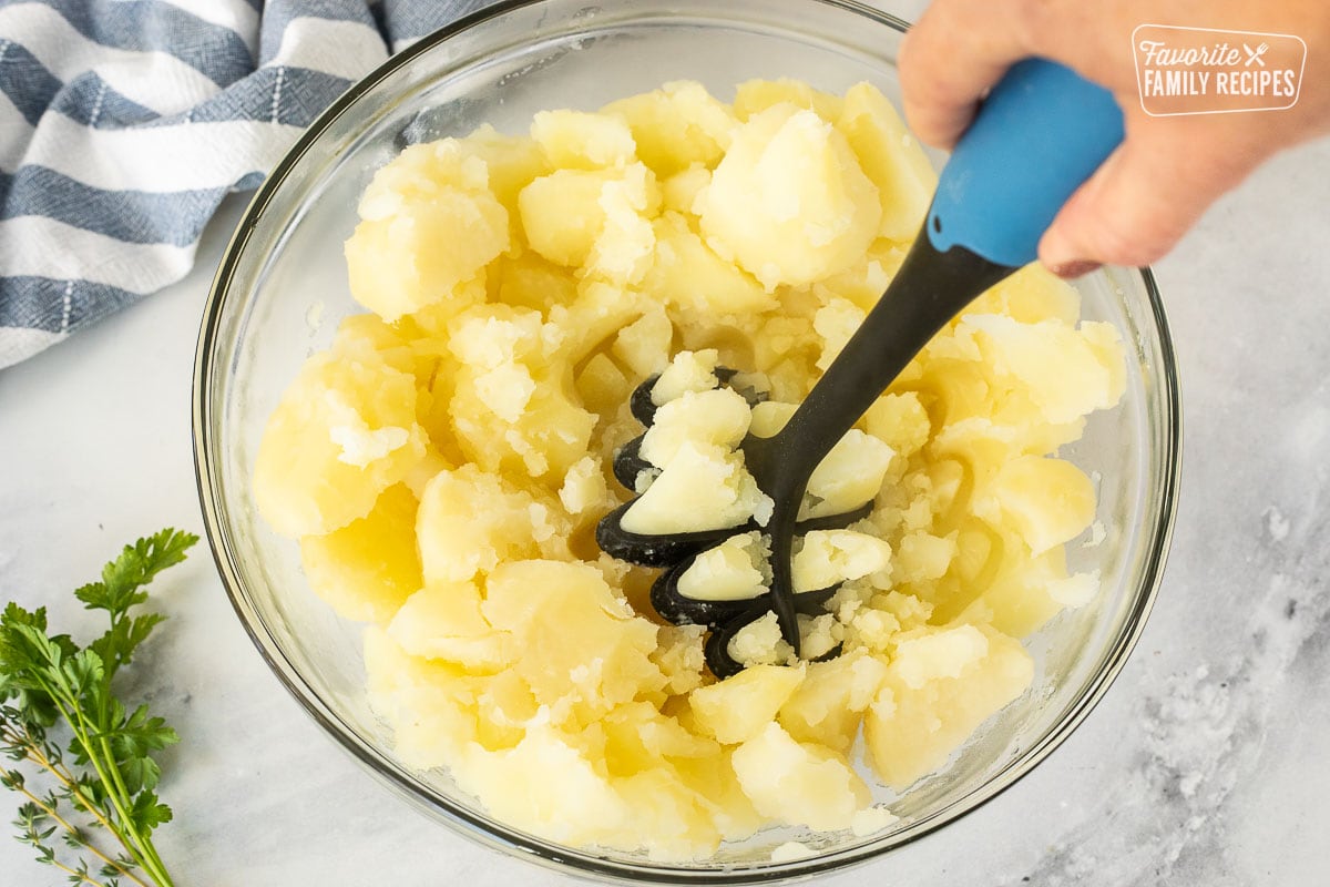 Smashing cooked potatoes in a bowl.