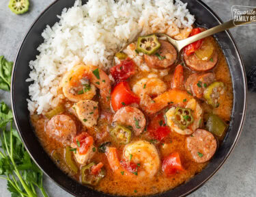 Instant Pot gumbo with shrimp, sausage, chicken, peppers, and other ingredients served in a dish with a bed of rice on the side.