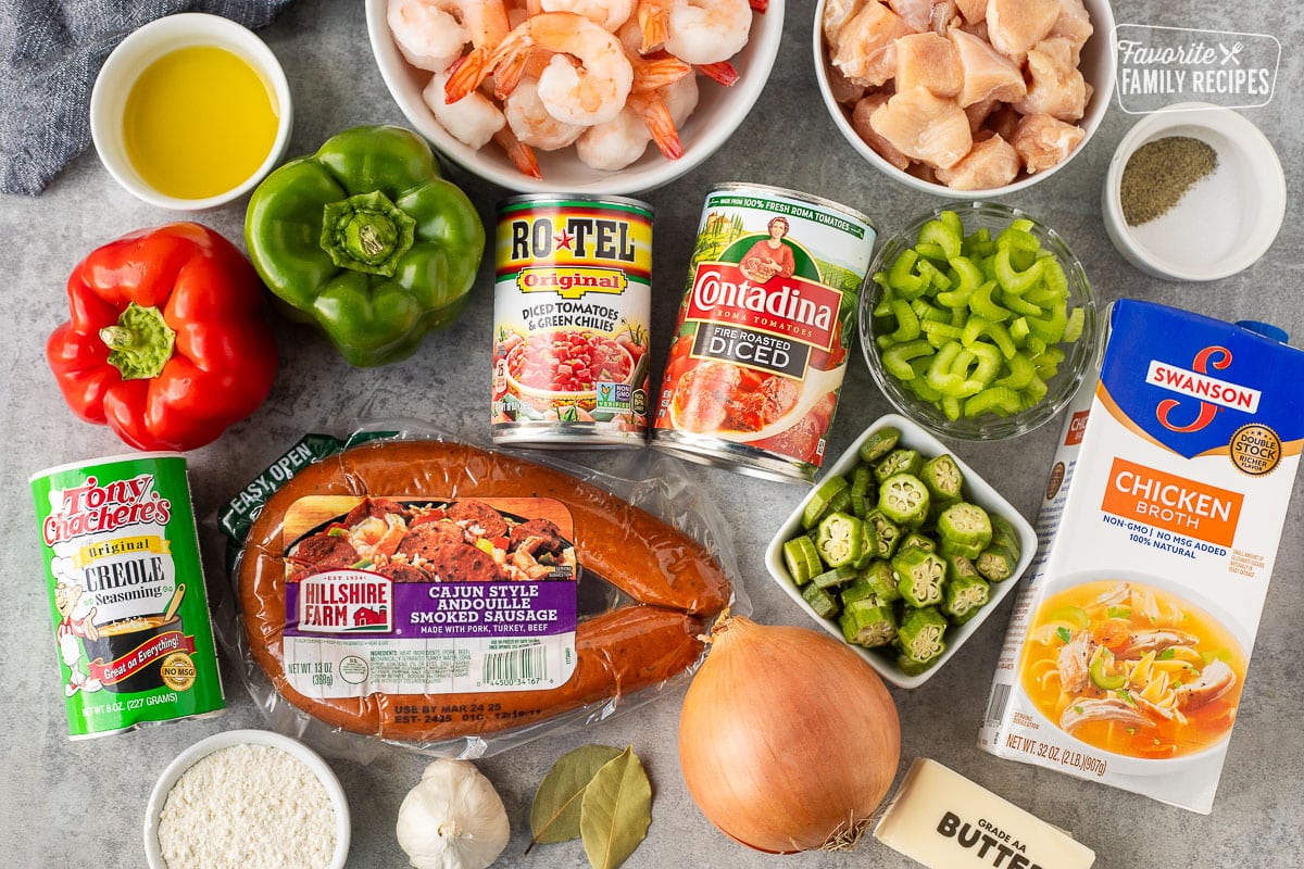 Ingredients to make Gumbo on a counter top including diced chicken, shrimp, andouille smoked sausage, chicken broth, peppers, okra, and seasonings.