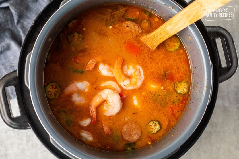 Shrimp added to instant pot gumbo. Wooden spoon resting in the instant pot.