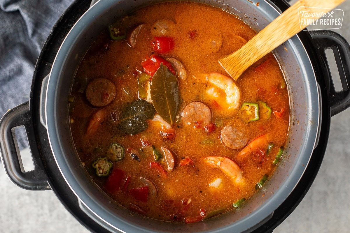 Shrimp, sausage, chicken, peppers, and bay leaves cooking in an Instant Pot to make gumbo.