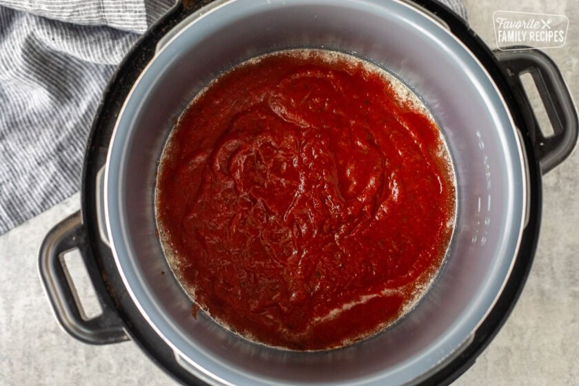 Instant pot with nonstick spray and spaghetti sauce.