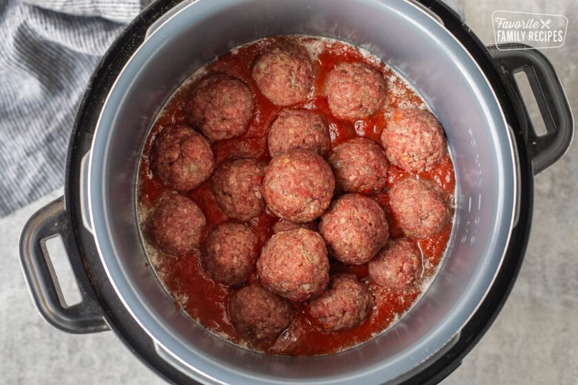 Instant pot with spaghetti sauce and raw meatballs.