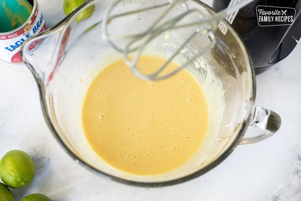 Key lime pie filling being mixed with electric beaters so the texture is smooth and creamy.