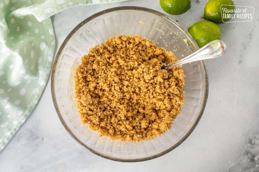 Graham cracker crumbs in a bowl with melted butter to make a key lime pie crust recipe.