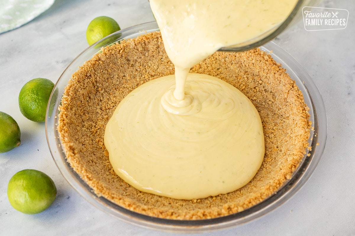 Filling being poured into a graham cracker crust of a key lime pie