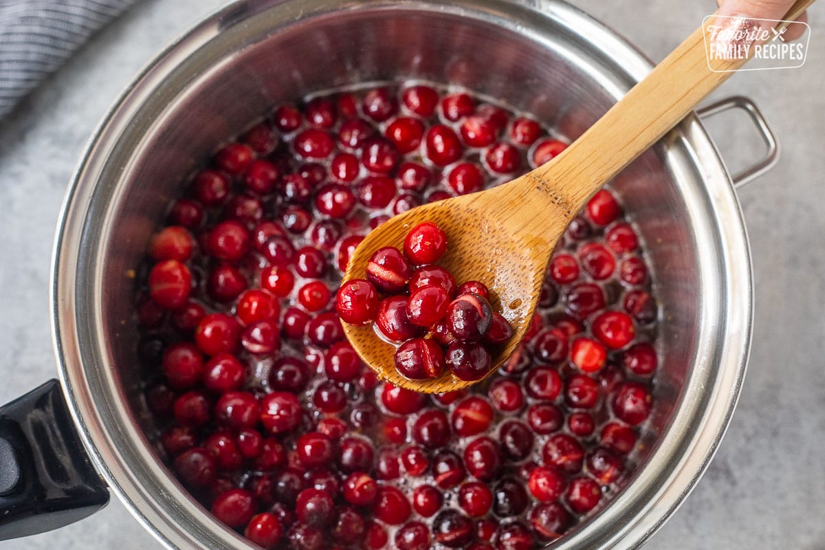 Cranberries heated and popping in a saucepan to make homemade orange cranberry sauce.