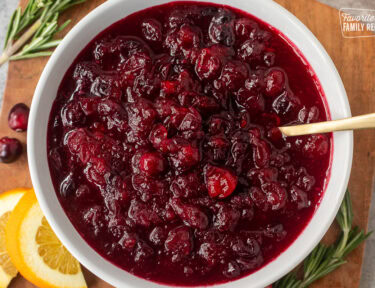 Large glass bowl of orange cranberry sauce with a spoon.