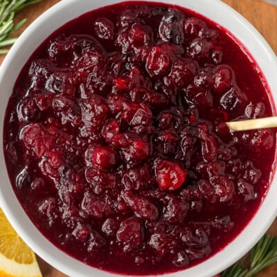 Large glass bowl of orange cranberry sauce with a spoon.