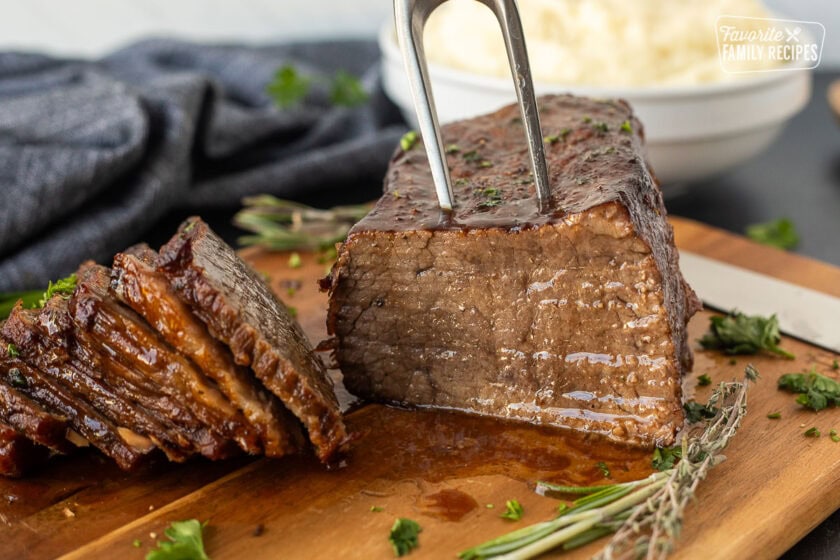 Cutting board with oven roast beef. Mashed potatoes on the side.