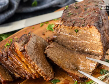 Fork in piece of oven roast beef on a cutting board.