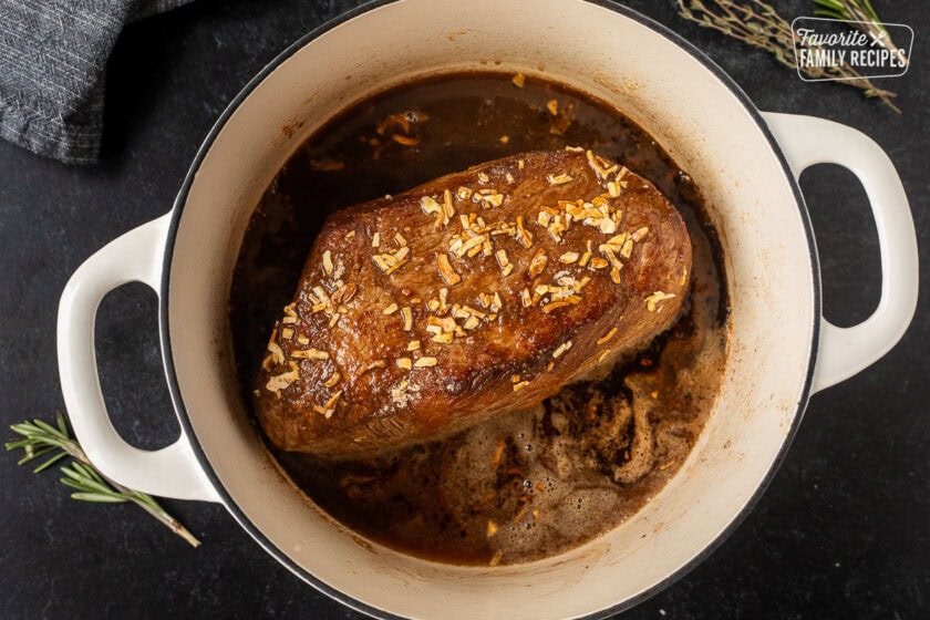 Dutch oven with browned oven roast with onion soup mix and broth.