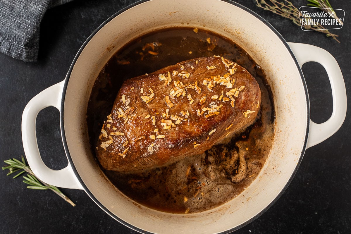 Dutch oven with browned oven roast with onion soup mix and broth.