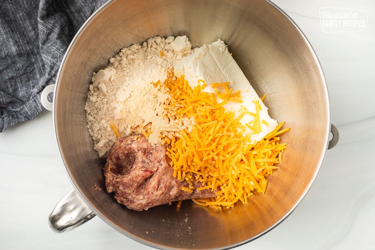 Mixing bowl with cheddar cheese, cream cheese, sausage and biscuit mix.