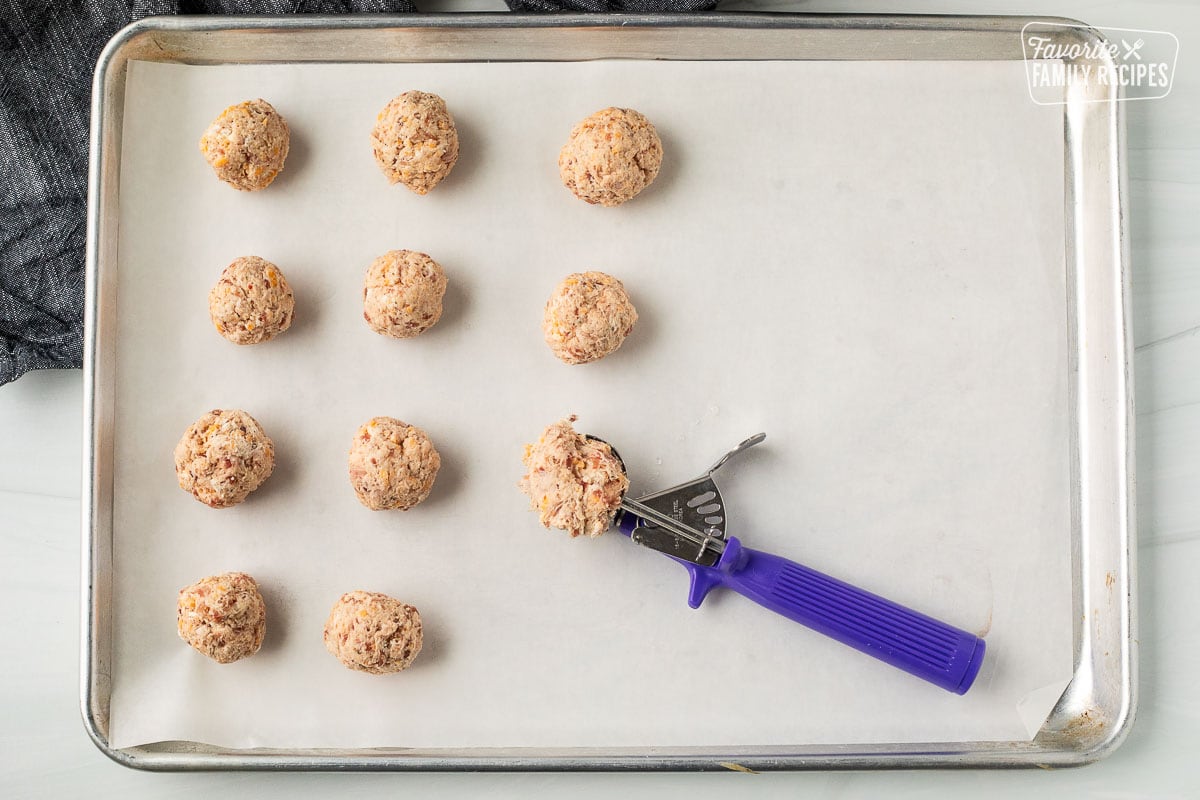 Scooped biscuit balls with a cookie scoop on a parchment lined baking sheet.