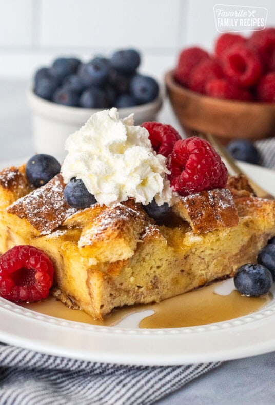 Plate with brioche French toast casserole, fresh blueberries, and raspberries and syrup.