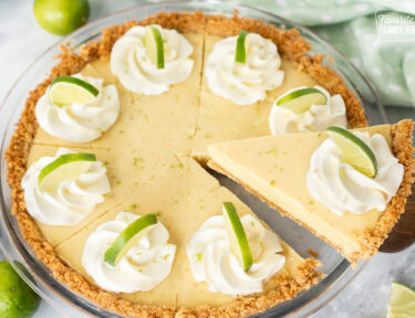 A slice of key lime pie being removed from the full pie with a pie knife