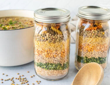 Two jars of dry soup ingredients. Pot of soup in the background.