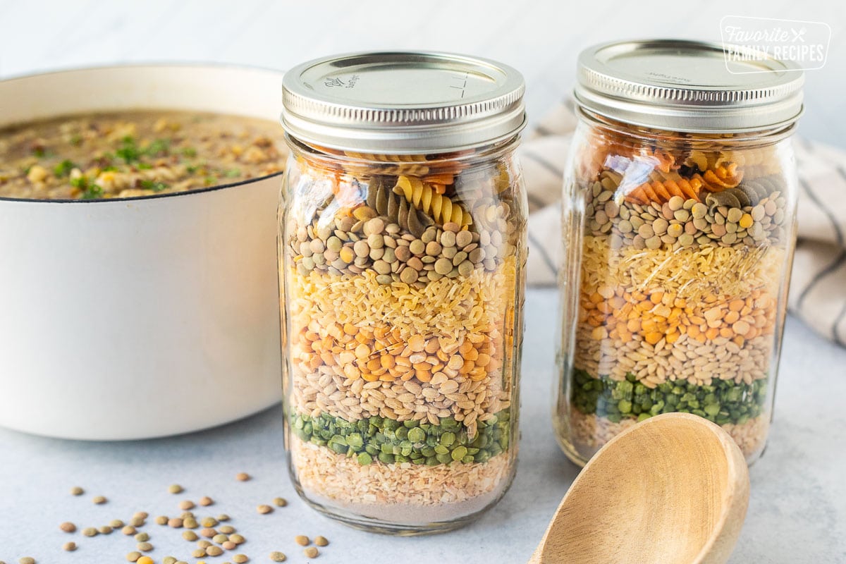 Two jars of dry soup ingredients. Pot of soup in the background.