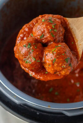 Wooden spoon holding up three instant pot meatballs.